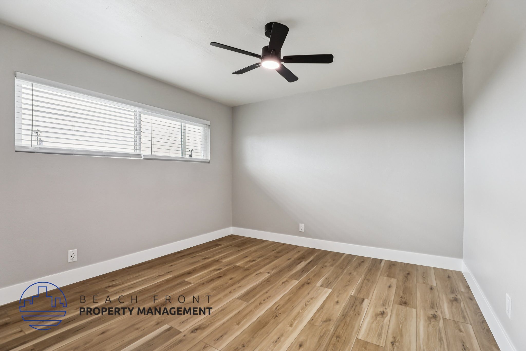 A room with a ceiling fan and wooden flooring.